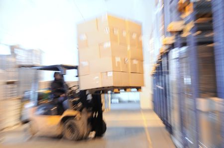 Electric forklift in warehouse loading cardboard boxes. Intentional optical zooming blurの写真素材
