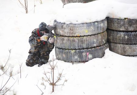 paintball sport player with mask aiming gun and shooting to enemy in winterの写真素材