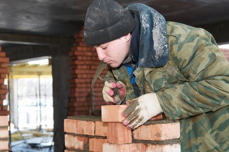 hands of a construction mason worker bricklayer making a brickwork with trowel