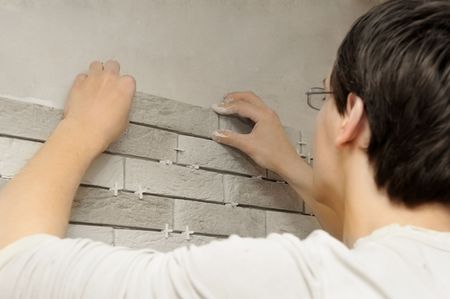 young worker tiler laying a tile on wallの写真素材