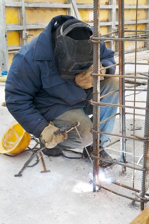 worker welding by electrode a metal lattice reinforcement for concrete pouring