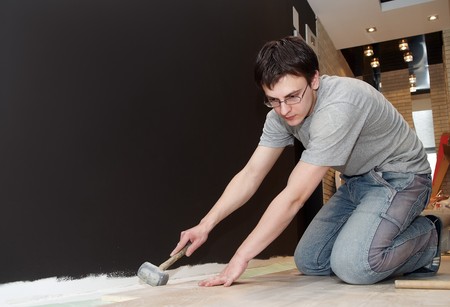 Young worker laying a floor with laminated flooring boardsの写真素材