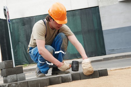 mason worker making sidewalk pavement with stone blocksの写真素材
