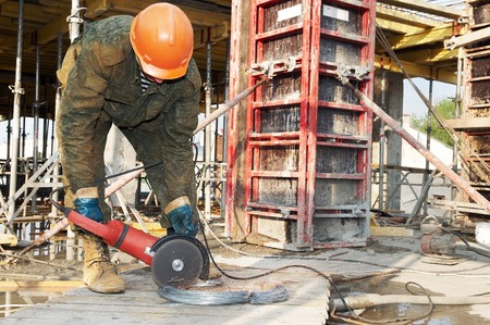 Builder works with circular abrasive cutoff saw and sparkles at construction siteの写真素材