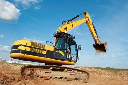 Loader Excavator standing in quarry with risen bucket over cloudscape sky 