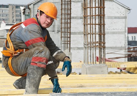Young builder worker in work wear, helmet and equipment at house building area