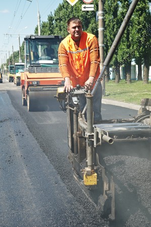 Young builder on Asphalting paver machine during Road street repairing works