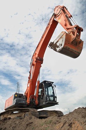 Loader Excavator doing construction works standing in field with risen bucket outdoors