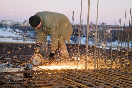 Builder works with circular abrasive cutoff saw and sparkles at construction siteの写真素材