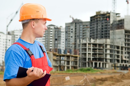 One builder worker with clipboard inspecting works at construction site