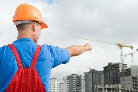engineer worker directing up with finger to building under constructionの写真素材