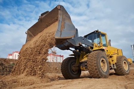 Wheel loader machine unloading sand at eathmoving works in construction siteの写真素材