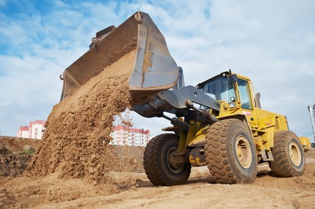 Wheel loader machine unloading sand at eathmoving works in construction siteの写真素材