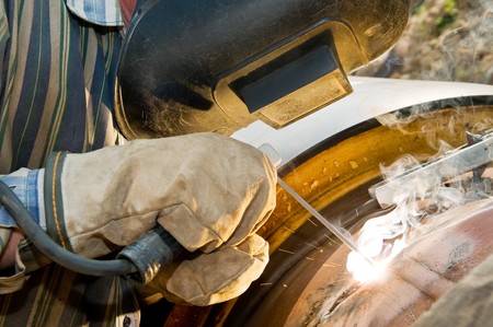 close-up welder works with electrode in protective helmet and gloves