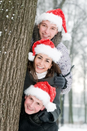 three cheerful young people in rad hats outdoorsの写真素材