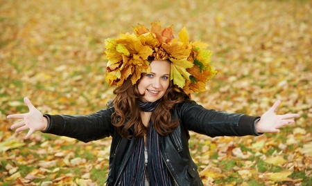 Woman with maple wreath at autumn outdoors