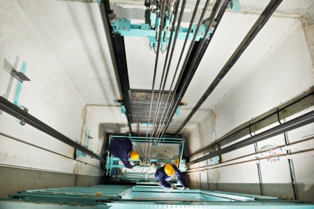 machinists adjusting lift in elevator hoistwayの写真素材