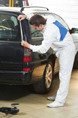 auto mechanic worker preparing car body for polishing at automobile repair and renew service station shopの写真素材