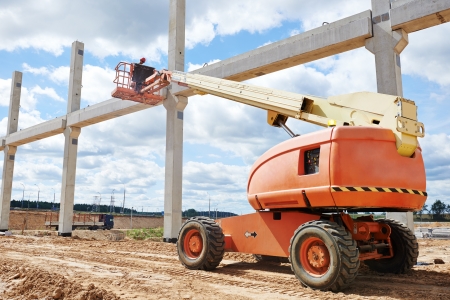 builder worker putting cement mortar on concrete pole joint at construction site using lifting boom machineryの写真素材