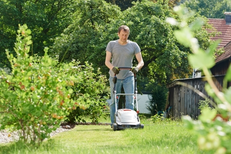man cutting grass in his garden yard with lawn mower