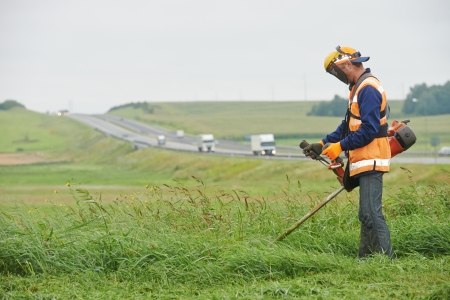 lawn mower worker man cutting grass in green field