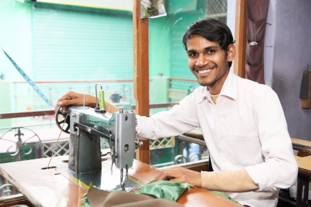 Portrait of indian man tailor at work place with sewing machine