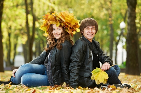 Two young smiling people with autumn maple leaves in park at fall outdoors dateの写真素材