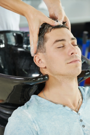 Washing man client hair in beauty parlour hairdressing salonの写真素材