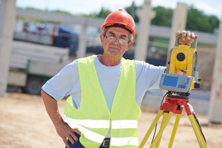 Portrait of builder worker with theodolite transit equipment at construction site outdoors during surveyor workの写真素材