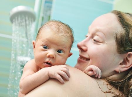 Bathing newborn baby with mother in water showerの写真素材