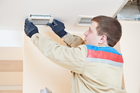 industrial builder installing ventilation or air conditioning filter holder in ceilingの写真素材