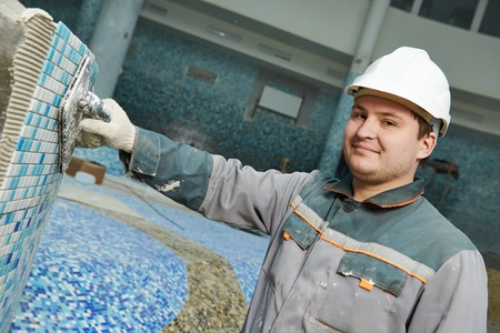 industrial tiler builder worker installing floor tile at repair renovation work