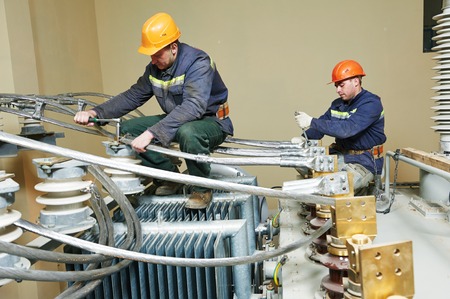 Electrician lineman repairman worker at huge power industrial transformer installation work