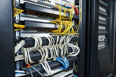 technology equipment with optical fibre cables connected to rack servers in room