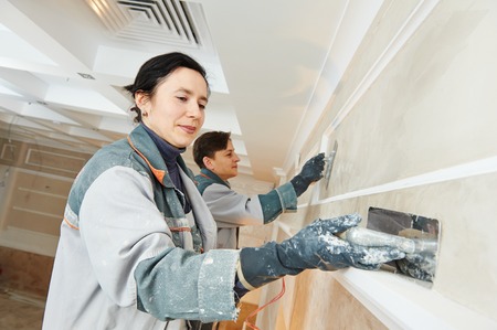 Plasterer at indoor wall renovation stucco decoration with float and plasterの写真素材