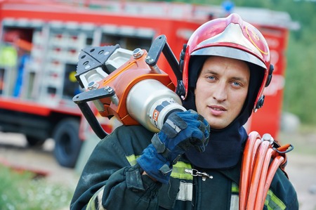 firefighter in uniform in front of fire engine machine and fireman team