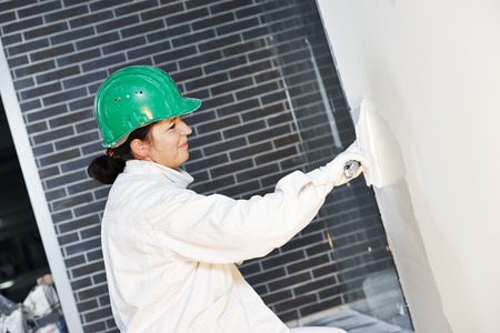 female plasterer at indoor wall renovation decoration with spatula and plasterの写真素材