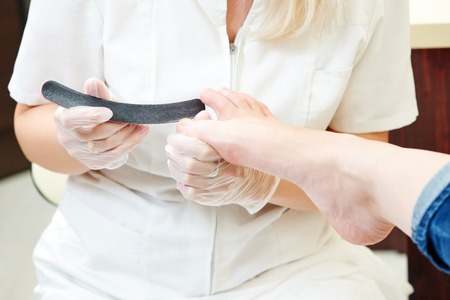 Pedicure nail technician worker perfoming procedure for foot care in beauty salonの写真素材