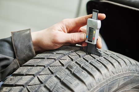 auto service man worker measuring rubber car wheel tyre protectorの写真素材