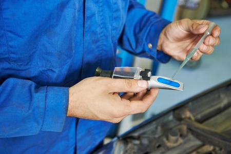 automobile mechanic tests car antifreeze liquid for winter and summerの写真素材