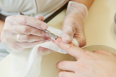 Manecurist perfoming finger nail procedure for hand care in beauty salonの写真素材