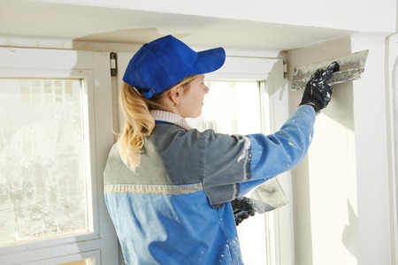female plasterer at indoor wall renovation decoration with spatula and plasterの写真素材