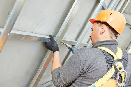 worker builder making construction for ventilation facade on a building with screwdriver drill