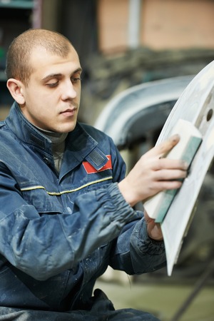 auto mechanic worker sanding polishing bumper car at automobile repair and renew service station shop by sandpaperの写真素材