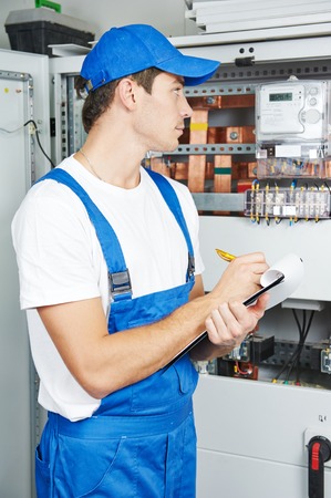 Young adult electrician builder engineer inspecting electric counter equipment in distribution fuse...