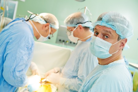 surgeons in uniform perform heart transplantation operation on a patient at cardiac surgery clinic