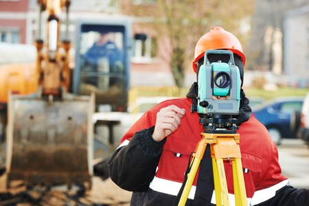 One surveyor worker working with theodolite transit equipment at road construction site outdoors