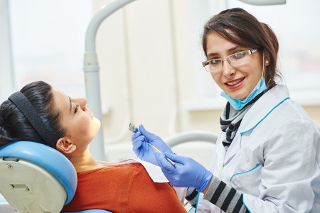 female asian dentist doctor during tooth examination and treatmentの写真素材