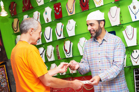 small shop owner indian man selling shawls, clothing and souvenirs at his storeの写真素材