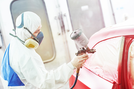 auto mechanic worker painting a red car in a paint chamber during repair workの写真素材